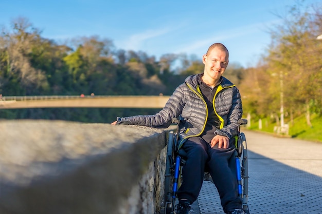 Eine behinderte Person im Rollstuhl in einem Park bei Sonnenuntergang neben einem Fluss bei Sonnenuntergang