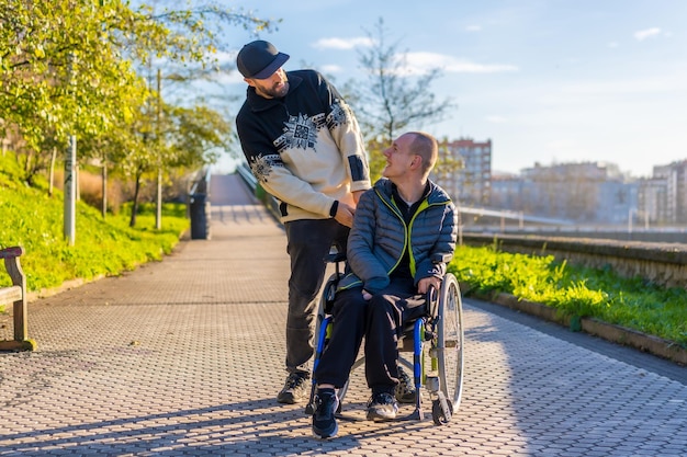 Eine behinderte Person im Rollstuhl mit einem Assistenten genießt einen Spaziergang in der Stadt