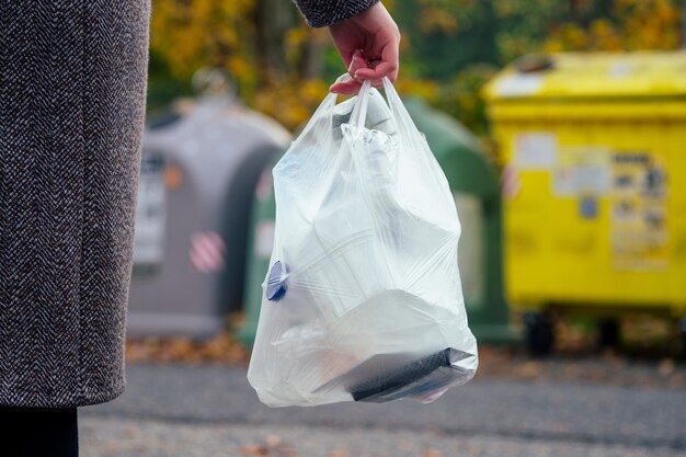 Eine bewusste Frau, die Papier von anderen Abfällen trennt und es in einen grünen Behälter legt, um natürliche Ressourcen in Prag Chezh zu sparen