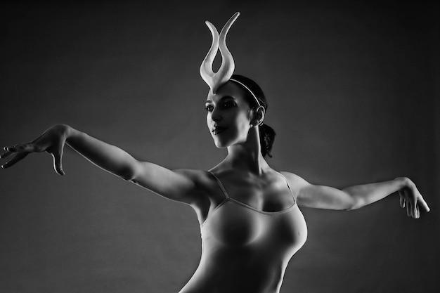 eine bezaubernde ballerina in einem bodysuit posiert ballettelemente in einem kopfschmuck in einem fotostudio