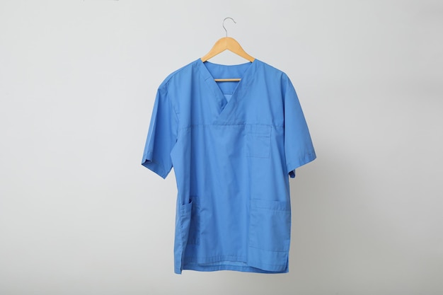 Eine blaue Arztuniform auf einem Kleiderbügel auf grauem Hintergrund