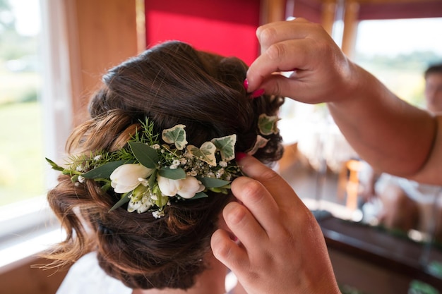 Eine Braut im Friseursalon, die Hochzeitskopfschmuck herstellt. Hände, die ein Haar der Braut berühren