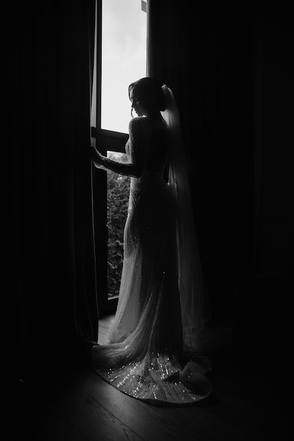eine Braut in einem Hochzeitskleid schaut aus einem Fenster
