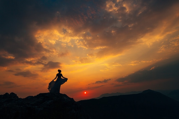 Eine Braut in einem Hochzeitskleid wirbelt auf der Spitze des Mount Lovcen bei Sonnenuntergang