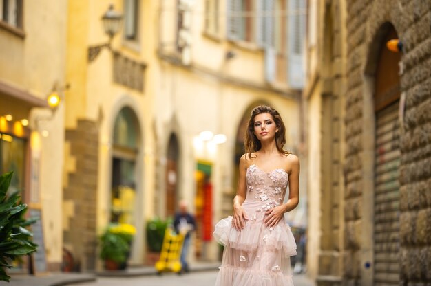 Eine Braut in einem rosa Hochzeitskleid geht in Florenz, Italien.