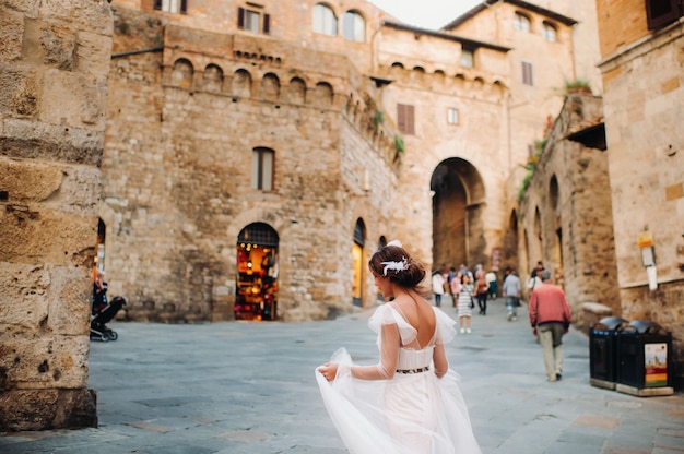 Eine Braut in einem weißen Kleid in der Altstadt von San Gimignano. Ein Mädchen geht durch die Stadt in Italien. Toskana.