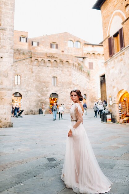 Eine Braut in einem weißen Kleid in der Altstadt von San Gimignano. Ein Mädchen geht durch die Stadt in Italien. Toskana.