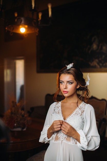 Eine Braut in Unterwäsche und ein weißes Gewand im Inneren einer Villa in Italien bei einer Hochzeit. Morgen der Braut in der Toskana. Boudoir-Fotosession in der Villa.