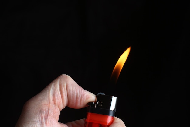 Foto eine brennende fackel von einem feuerzeug in den händen auf einem schwarzen