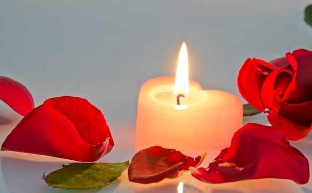 Eine brennende Kerze in Rosenblättern