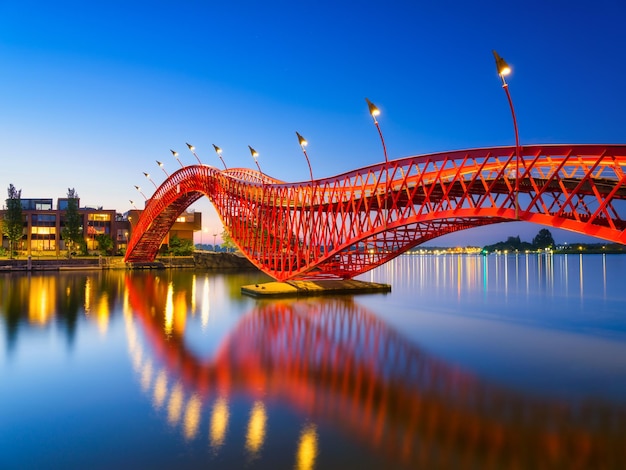 Eine Brücke in der Stadt bei Nacht Die Brücke auf dem Hintergrund des blauen Himmels während der blauen Stunde Architektur und Design Die Python-Brücke Amsterdam Niederlande