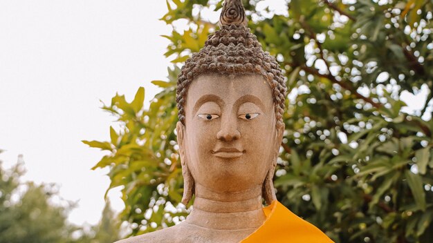 Eine Buddha-Statue mit gelber Schärpe und Augen.