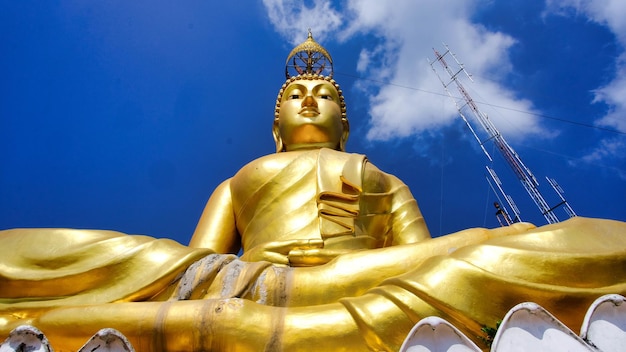 Eine Buddha-Statue sitzt vor einem blauen Himmel.