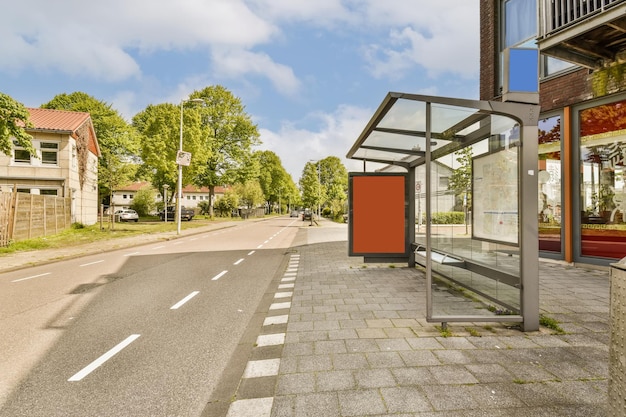 Eine Bushaltestelle mitten in einer leeren Straße mit Gebäuden und Bäumen auf beiden Seiten, von der Seite gesehen