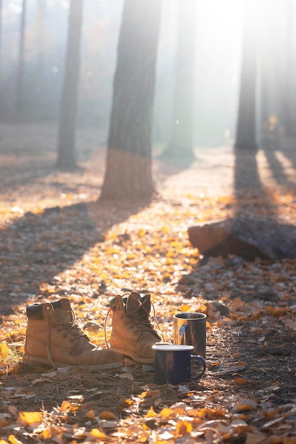 Eine Camping-Ästhetik. Tassen mit Tee und Stiefel im Morgenlicht