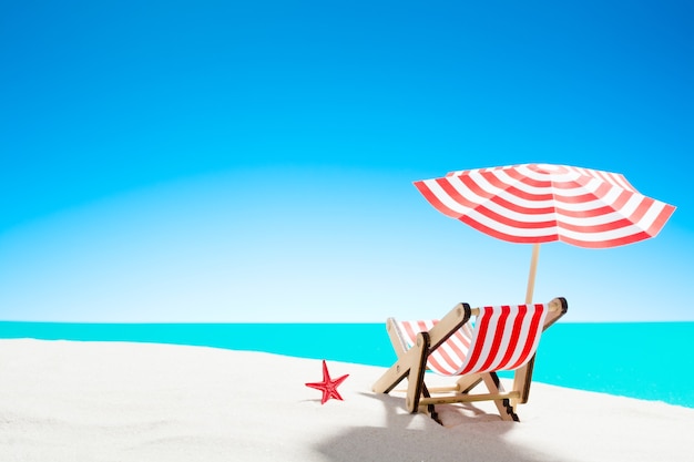 Eine Chaiselongue unter einem Regenschirm am Sandstrand am Meer und Himmel mit Kopierraum