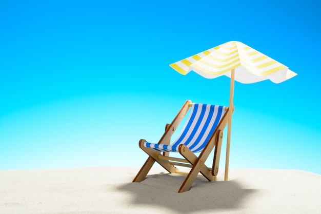 Eine Chaiselongue unter einem Regenschirm am Sandstrand