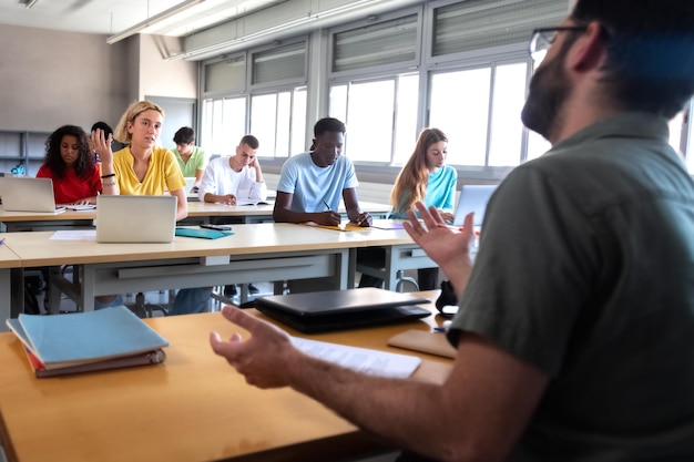 Eine College-Studentin spricht während eines Vortrags mit einem Professor, ein Student unterhält sich mit einem Lehrer.