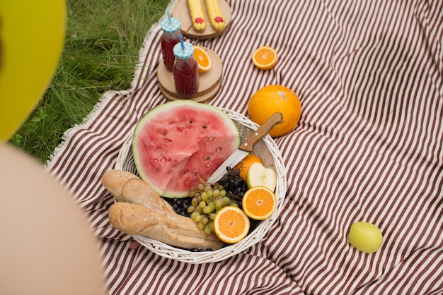 Eine Decke und ein Korb mit Obst und Wassermelone im Park im Sommer an einem sonnigen Tag