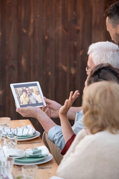 Eine der Frauen winkt einem jungen Paar auf dem Tablet-Display zu