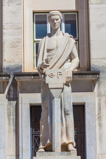 Eine detaillierte Ansicht einer Statue eines Mannes, möglicherweise eines Philosophen oder Gelehrten, der ein Buch und eine Feder hält