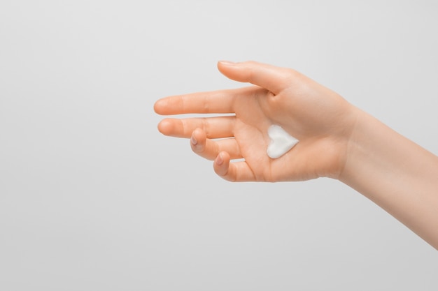 Eine dicke herzförmige Creme auf der Hand einer Frau. Gepflegte Hände, natürliche kurze Nägel, auf hellem Hintergrund.