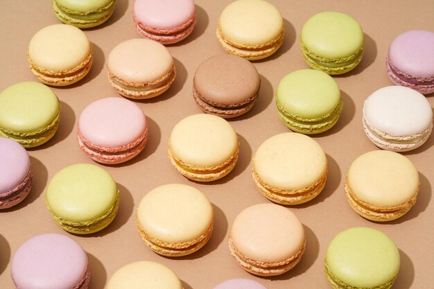 Eine Draufsicht auf eine beige Tischoberfläche mit einer Reihe bunter Macarons in ordentlichen Reihen