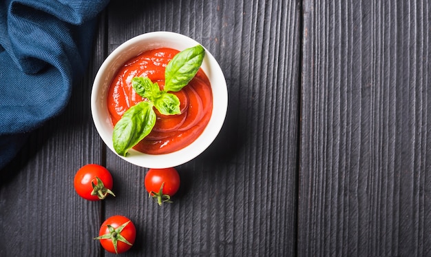 Eine Draufsicht der frischen Tomatensauce mit Stoff auf hölzerner Planke