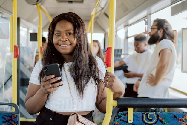 Eine dunkelhäutige Frau fährt in einem Linienbus und hält sich an einer Schranke fest