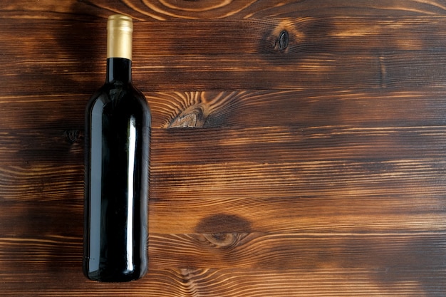 Eine dunkle Flasche Wein auf einem Holztisch