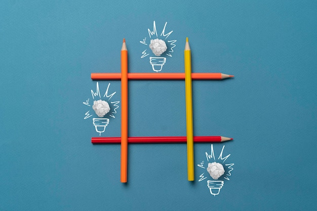 Eine einfache kreative Idee von gezeichneten Papierglühbirnen im Tic-Tac-Toe-Gitter aus Buntstiften auf pastellfarbenem Hintergrund