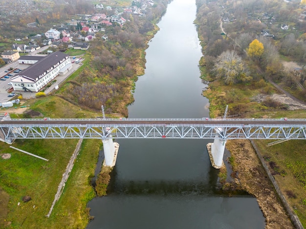 Eine eingleisige Eisenbahnbrücke über den Fluss in der Stadt Draufsicht auf die Brücke in einem wunderschönen grünen Park Fliegen einer Drohne über eine Eisenbahnbrücke im Nebel Herbstlandschaft