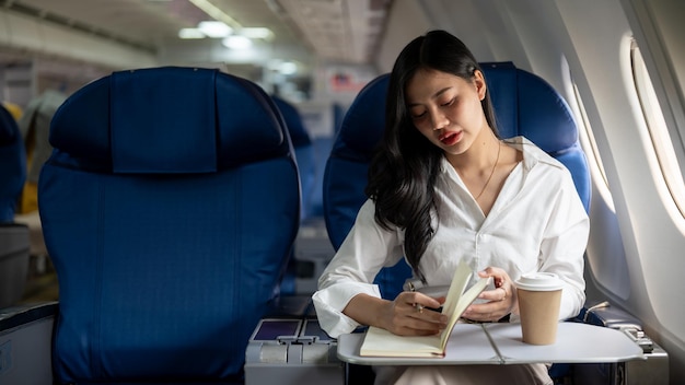 Eine elegante asiatische Geschäftsfrau ist in einem Flugzeug auf dem Weg zu einer anderen Stadt für ein Geschäftstreffen