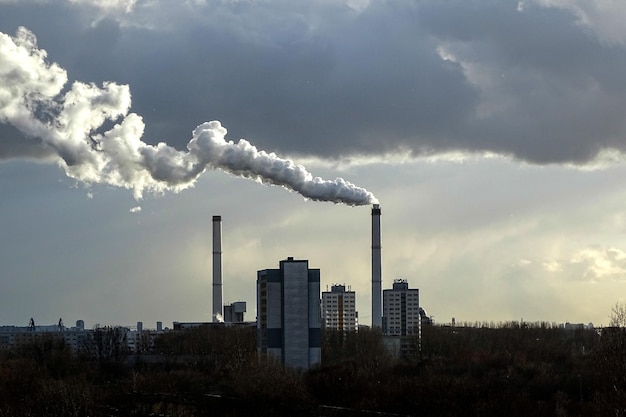 Eine entfernte Fabrik, die Rauch gegen einen bewölkten Himmel ausstrahlt