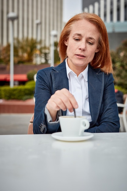 Eine erfolgreiche Geschäftsfrau mittleren Alters, die sich einen Moment Zeit nimmt, um neue Energie zu tanken, genießt eine friedliche Kaffeepause