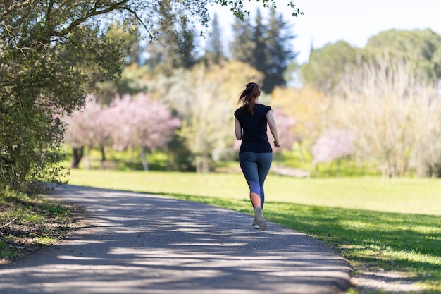 Eine erwachsene Frau in grauen Leggings, die in der Natur joggt