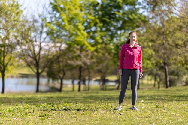 Eine erwachsene lächelnde Frau in Sportkleidung, die auf dem Feld steht