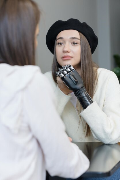 Eine Europäerin mit einer bionischen Prothese am Arm unterhält sich an einem öffentlichen Ort mit Freunden. Behinderung oder Amputation von Gliedmaßen, bionische Prothetik von Unterarm, Hand und Fingern. Prothetik