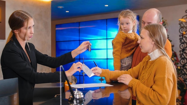 Eine Familie, die im Luxushotel eincheckt, erhält von einer Frau an der Rezeption eine Broschüre und Schlüssel