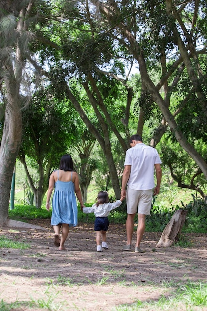 Foto eine familie geht durch einen park mit einem kind, das sich die hände hält