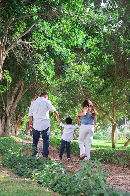 Foto eine familie geht mit den händen in der luft durch einen park