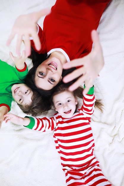 Eine Familie im gestreiften Pyjama ruht sich zu Hause aus. Auf dem Sofa liegen kleine, als Elfen verkleidete Kinder. Eine glückliche Familie.