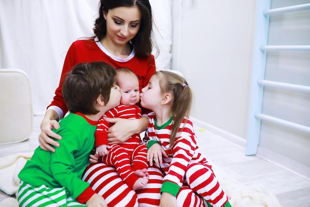 Eine Familie im gestreiften Pyjama ruht sich zu Hause aus. Auf dem Sofa liegen kleine, als Elfen verkleidete Kinder. Eine glückliche Familie.