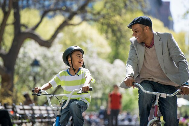 Eine Familie im Park an einem sonnigen Tag Radfahren und Spaß haben Vater und Sohn Seite an Seite