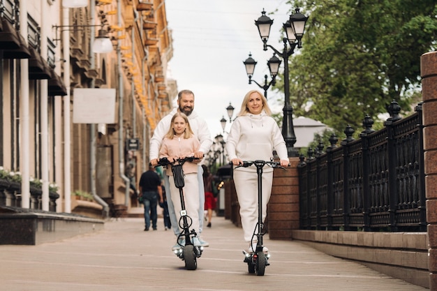 Eine Familie in weißen Kleidern fährt Elektroroller in der Stadt. Outdoor-Aktivitäten.