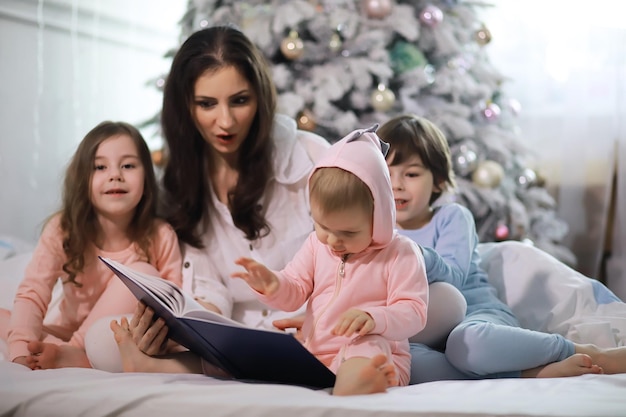 Eine Familie mit Kindern, die sich in den Weihnachtsferien auf dem Bett unter der Bettdecke vergnügt