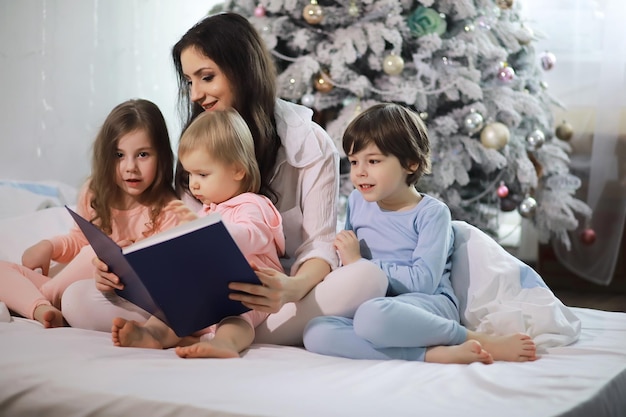 Eine Familie mit Kindern, die sich in den Weihnachtsferien auf dem Bett unter der Bettdecke vergnügt