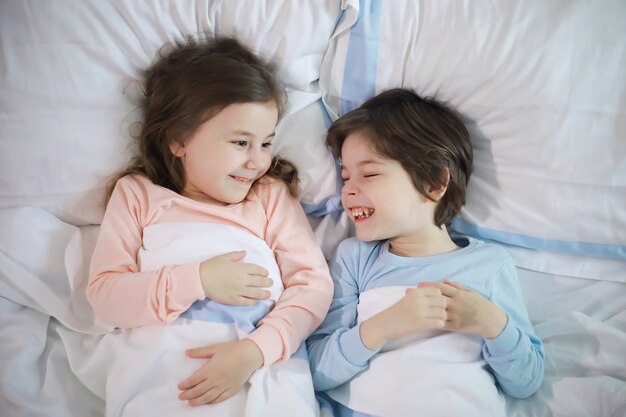 Eine Familie mit Kindern, die sich während der Weihnachtsferien auf dem Bett unter der Bettdecke amüsieren.