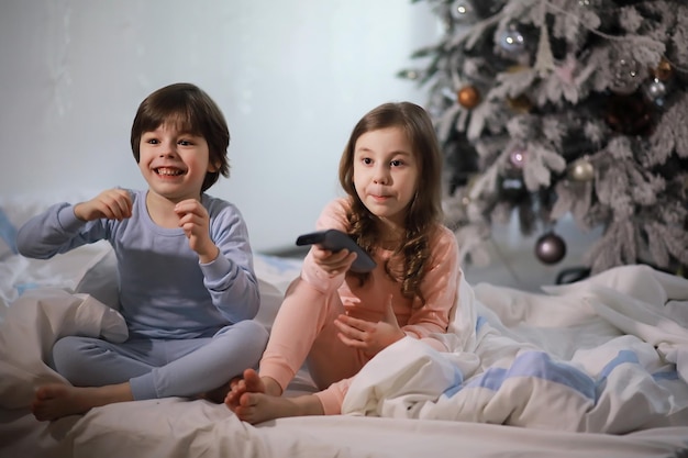 Eine Familie mit Kindern, die sich während der Weihnachtsferien auf dem Bett unter der Bettdecke amüsieren.