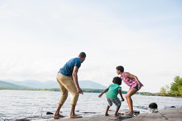 Eine Familie, Mutter, Vater und Sohn, die am Ufer eines Sees spielen